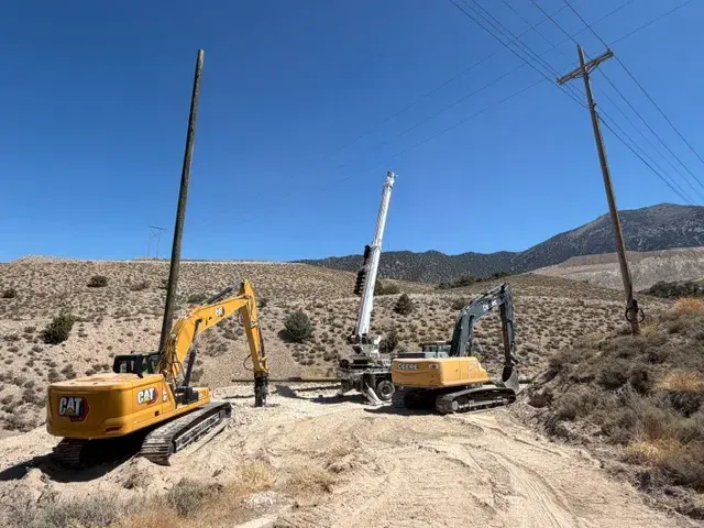 Excavators and utility poles on rocky terrain