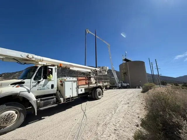 Field truck beside utility poles on a dirt road