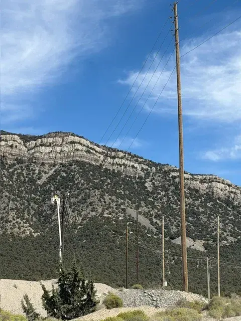 Overhead utility pole against a mountain backdrop