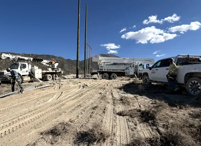 Field vehicles beside poles on a dirt access road