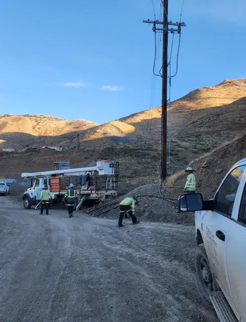 Field vehicles beside a utility pole on a hillside